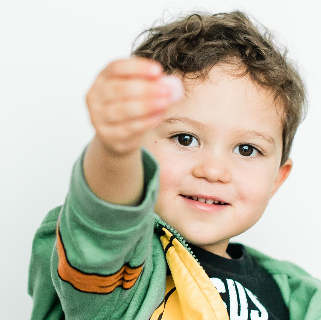 toddler showing Raise Them Well children's multivitamin chewable tablet