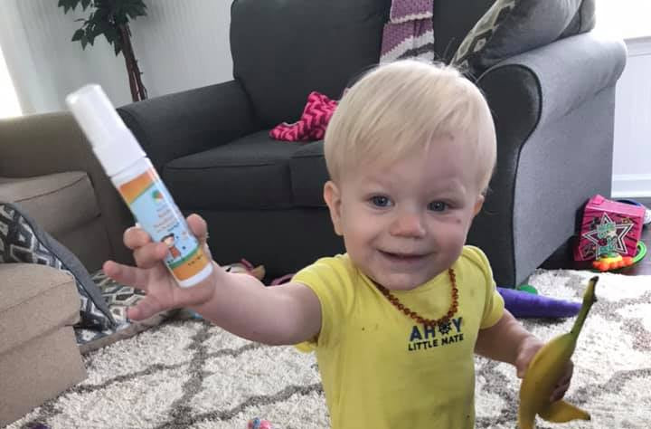 cute toddler carrying bottle of Raise Them Well kid-safe certified toxic-free hand and surface sanitizer