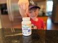 Children's chewable probiotic bottle on a kitchen counter with a child in the background.